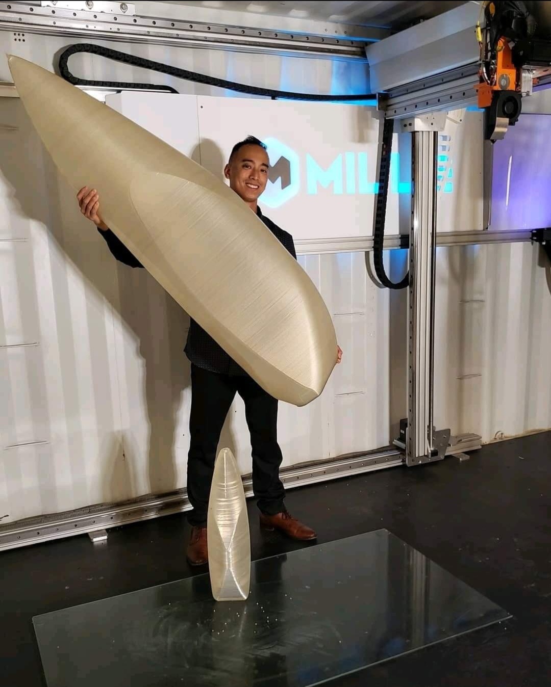 Andy Tran holding a large-format 3D-printed hull form inside the container printer he invented